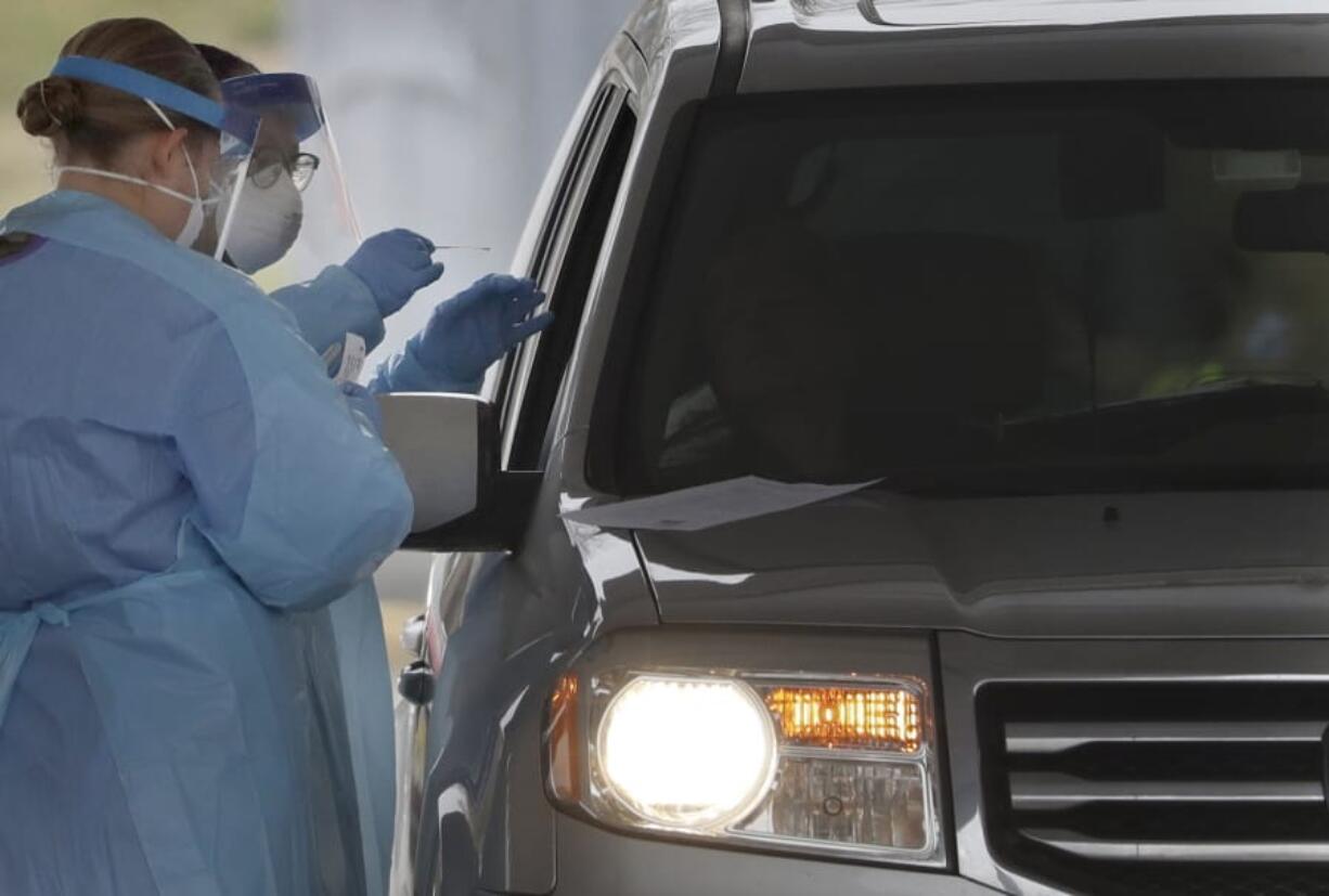 FILE - In this March 20, 2020, file photo, people in protective gear administer a test for the new coronavirus at a drive-thru testing center in Paramus, N.J. Feeling sick and stressed, people in the states hardest hit by the coronavirus have continued to stream into drive-thru testing sites, hoping to get guidance about whether to seek treatment, or reassurance that they aren&#039;t infected.