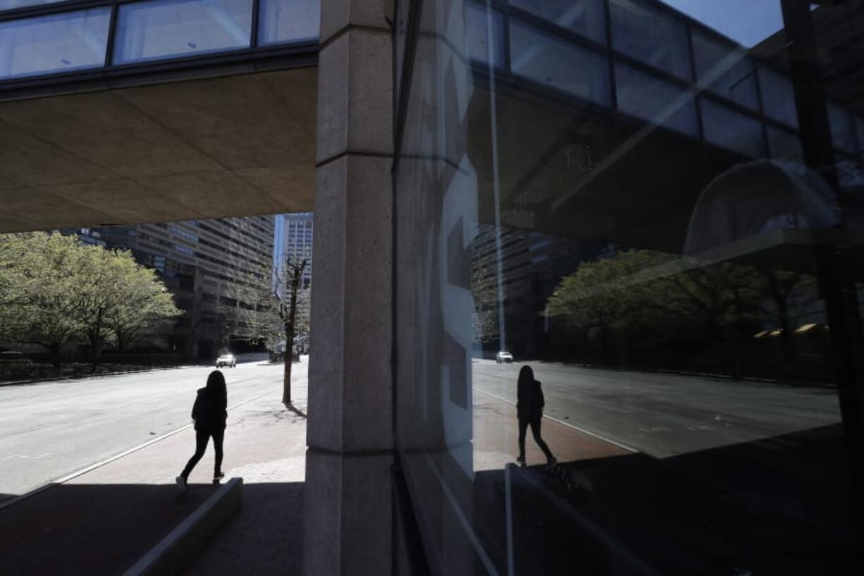 A person walks along a nearly empty street Wednesday, April 29, 2020, in Boston. Job cuts have escalated across the U.S. economy in recent days that remains all but shut down due measures taken to halt the spread of the virus.