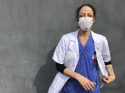 In this photo taken on Tuesday, April 7, 2020, Aurelie Gouel, an ICU doctor, poses during a break in her shift treating COVID-19 patients at Bichat Hospital in Paris. Gouel was infected by the new coronavirus in March but rushed back to work as soon as she recovered from her high fever, cough and other symptoms because she felt compelled to rejoin the fight to save lives.  The coronavirus has infected so many doctors, nurses and other health workers that some are now returning to work hoping that they are now armed with some degree of immunity.