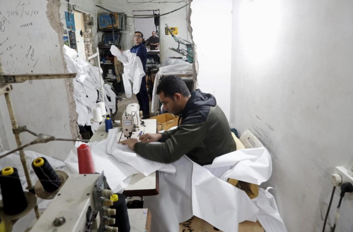 FLE - In this Monday, March 30, 2020 file photo, Palestinians make protective overalls meant to shield people from the coronavirus, to be exported to Israel, at a local factory, in Gaza City.