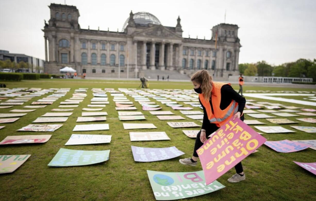 Luisa Neubauer of Fridays for Future movement lays out protest posters for climate protection in front the German parliament building the Reichstag in Berlin, Germany, Friday, April 24, 2020. Because of the continuing spread of the coronavirus, the climate strike will be digitally distributed on the Internet.