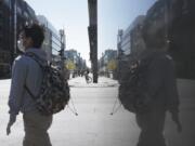 A man with a face mask walks over the Friedrichstrasse, a main shopping street, in Berlin, Germany, Wednesday, April 22, 2020. Smaller shops allowed to open in the German capital from today on.