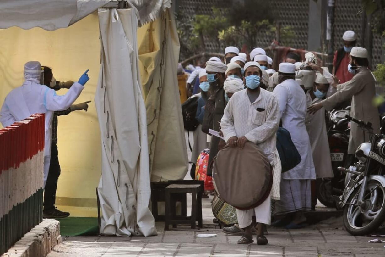 FILE - In this March 31, 2020, file photo, Indian paramedics note down the names of Muslims after screening them before they board a bus, after a government raid discovered the largest viral cluster in India at the Nizamuddin area of New Delhi, India.