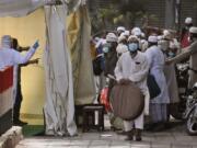 FILE - In this March 31, 2020, file photo, Indian paramedics note down the names of Muslims after screening them before they board a bus, after a government raid discovered the largest viral cluster in India at the Nizamuddin area of New Delhi, India.