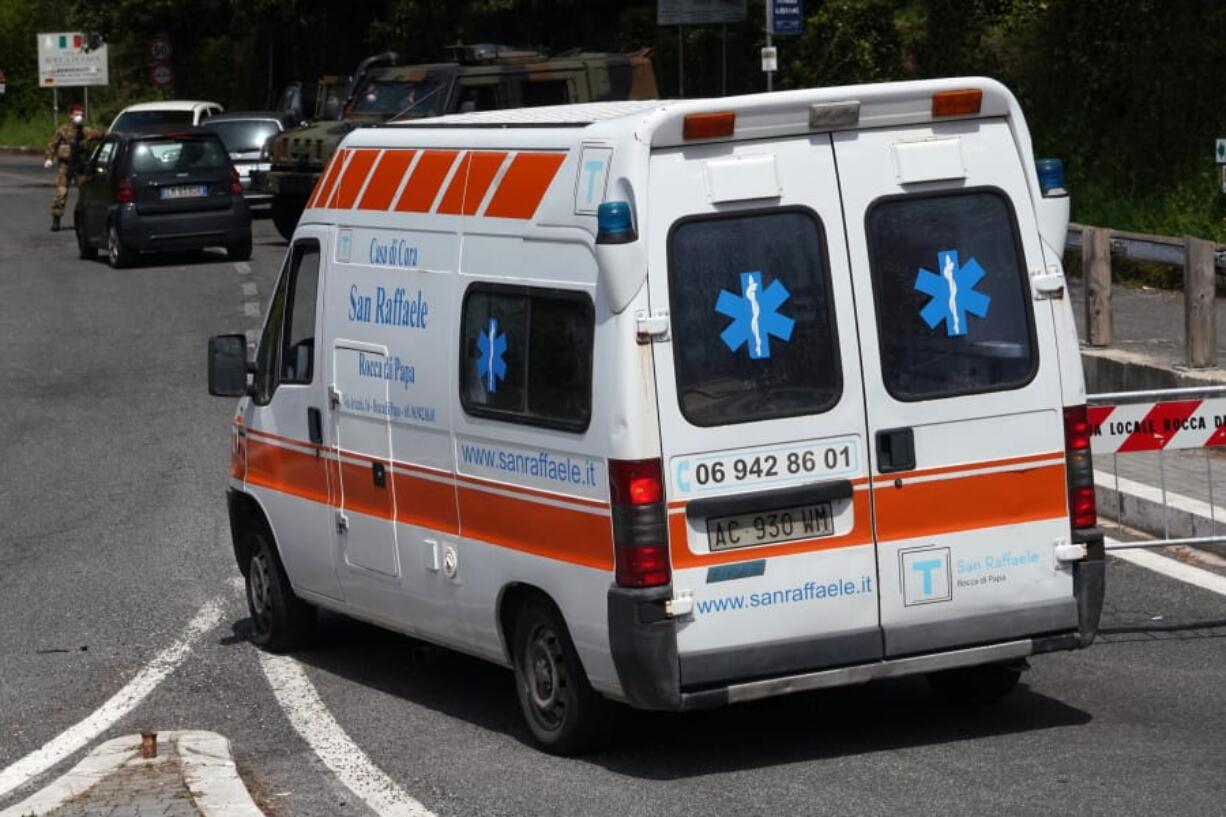 An ambulance of the San Raffaele health care and hospice structure drives past a road block on its way to the San Raffaele hospice after, according to reports, over 70 people inside tested positive to the new coronavirus, in Rocca di Papa, near Rome, Friday, April 17, 2020.