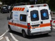 An ambulance of the San Raffaele health care and hospice structure drives past a road block on its way to the San Raffaele hospice after, according to reports, over 70 people inside tested positive to the new coronavirus, in Rocca di Papa, near Rome, Friday, April 17, 2020.