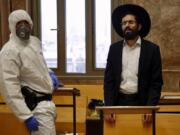 An Israeli police officer wearing protective gear waits to detain an ultra-Orthodox man as he prays in a synagogue because of the government&#039;s measures to help stop the spread of the coronavirus, in Bnei Brak, a suburb of Tel Aviv, Israel, Thursday, April 2, 2020. ?On Wednesday, Israeli Prime Minister Benjamin Netanyahu ordered a police cordon around the largely ultra-Orthodox city of Bnei Brak, to limit movement to and from the city. Bnei Brak has the second highest number of coronavirus cases in Israel.