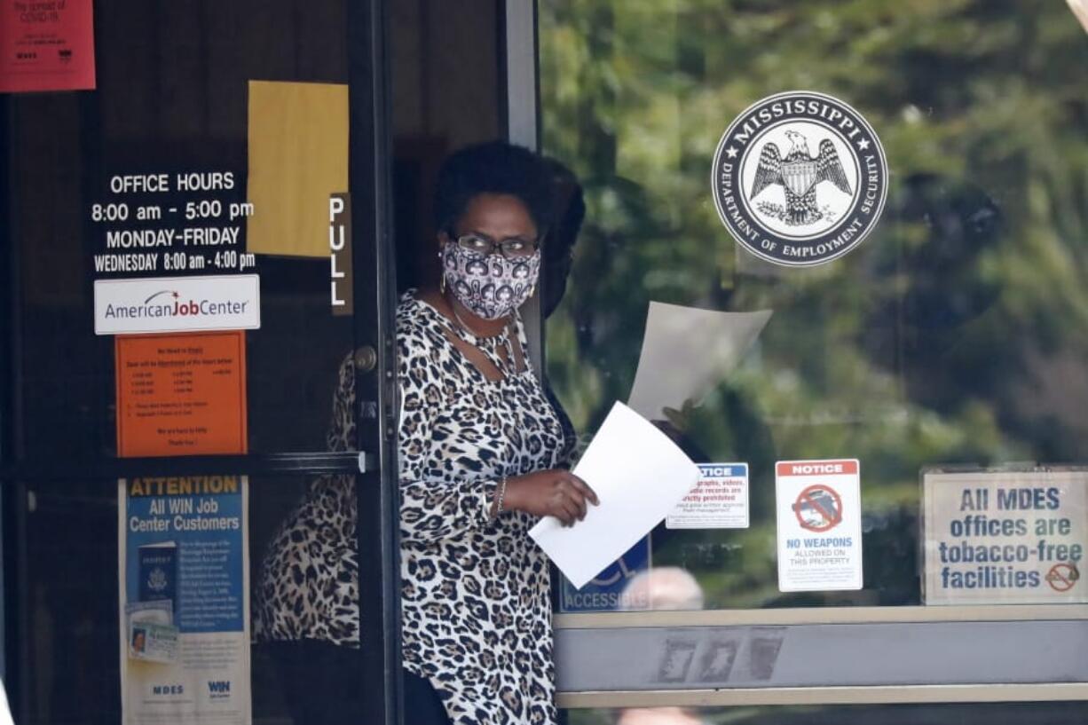 A masked worker at this state WIN job center in Pearl, Miss., holds an unemployment benefit application form as she waits for a client, Tuesday, April 21, 2020. The job centers lobbies are closed statewide to prevent the spread of COVID-19. However the continuing growth of unemployment demands and now additional assistance for self-employed, church employees, gig workers, and others who were previously ineligible for unemployment assistance has drawn some people to the centers for information and to obtain and submit unemployment benefit applications. (AP Photo/Rogelio V.