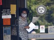 A masked worker at this state WIN job center in Pearl, Miss., holds an unemployment benefit application form as she waits for a client, Tuesday, April 21, 2020. The job centers lobbies are closed statewide to prevent the spread of COVID-19. However the continuing growth of unemployment demands and now additional assistance for self-employed, church employees, gig workers, and others who were previously ineligible for unemployment assistance has drawn some people to the centers for information and to obtain and submit unemployment benefit applications. (AP Photo/Rogelio V.