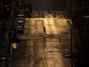 A man walks a dog on an empty downtown street as the sun sets Wednesday, April 1, 2020, in Kansas City, Mo.