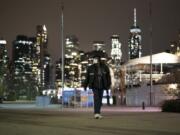 A man wearing a mask walks through Brooklyn Bridge Park, Tuesday night, April 14, 2020 during the coronavirus pandemic in New York. Known as &quot;The City That Never Sleeps,&quot; New York&#039;s streets are particularly empty during the pandemic.