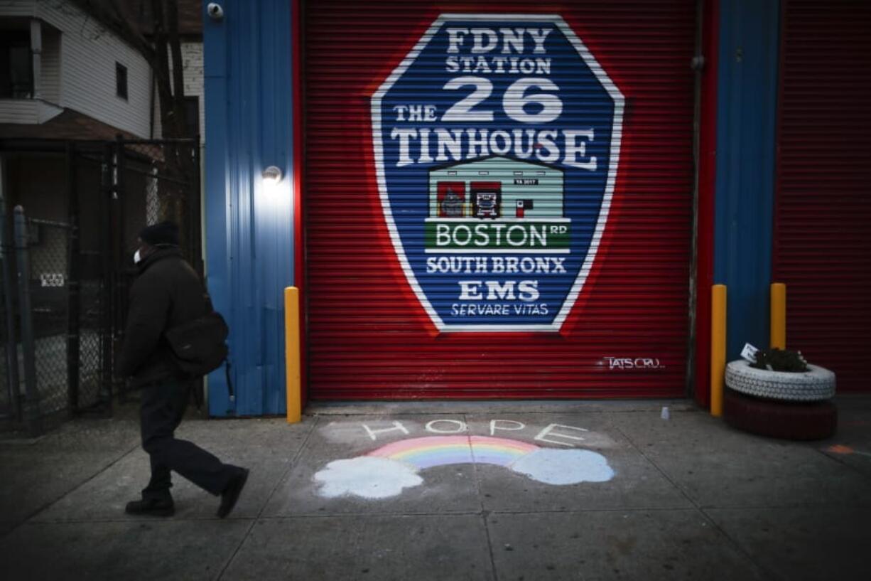 A pedestrian wearing personal protective equipment to protect against the spread of coronavirus, passes EMS station 26, the Tinhouse&quot; Thursday, April 23, 2020 in the Bronx borough of New York.