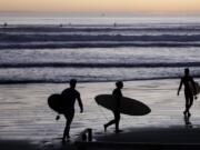 Surfers prepare to enter the water at Sumner Beach as level four COVID-19 restrictions are eased in Christchurch, New Zealand, Tuesday, April 28, 2020. New Zealand eased its strict lockdown restrictions to level three at midnight to open up certain sections of the economy but social distancing rules will still apply.