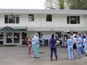 In this Friday, April 17, 2020, photo, Dr. Thaun Ong, just right of center, holds a notepad while he gives instructions to a team of University of Washington medical providers as they prepare to conduct testing for the new coronavirus at Queen Anne Healthcare, a skilled nursing and rehabilitation facility in Seattle. Sending &quot;drop teams&quot; from University of Washington Medicine to conduct universal testing at skilled nursing facilities in collaboration with public health officials is one aspect of the region&#039;s approach to controlling the spread of the coronavirus. (AP Photo/Ted S.