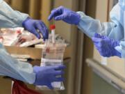 A vial used to collect a nose swab sample is put into a collection bag as members of a team of University of Washington medical providers conduct coronavirus testing at Queen Anne Healthcare, a skilled nursing and rehabilitation facility in Seattle. More than 100 residents were tested during the visit, and the results for all were negative, according to officials. (AP Photo/Ted S.