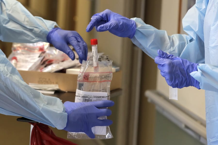 A vial used to collect a nose swab sample is put into a collection bag as members of a team of University of Washington medical providers conduct coronavirus testing at Queen Anne Healthcare, a skilled nursing and rehabilitation facility in Seattle. More than 100 residents were tested during the visit, and the results for all were negative, according to officials. (AP Photo/Ted S.