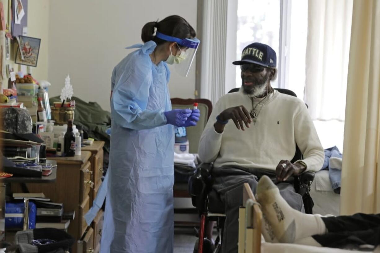 In this Friday, April 17, 2020, photo, Dr. Gabrielle Beger, left, prepares to take a nose-swab sample from Lawrence McGee, as she works with a team of University of Washington medical providers conducting testing for the new coronavirus at Queen Anne Healthcare, a skilled nursing and rehabilitation facility in Seattle. Sending &quot;drop teams&quot; from University of Washington Medicine to conduct universal testing at skilled nursing facilities in collaboration with public health officials is one aspect of the region&#039;s approach to controlling the spread of the coronavirus. (AP Photo/Ted S.