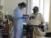 In this Friday, April 17, 2020, photo, Dr. Gabrielle Beger, left, prepares to take a nose-swab sample from Lawrence McGee, as she works with a team of University of Washington medical providers conducting testing for the new coronavirus at Queen Anne Healthcare, a skilled nursing and rehabilitation facility in Seattle. Sending &quot;drop teams&quot; from University of Washington Medicine to conduct universal testing at skilled nursing facilities in collaboration with public health officials is one aspect of the region&#039;s approach to controlling the spread of the coronavirus. (AP Photo/Ted S.