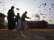 In this Tuesday, March 31, 2020, photo, staff from the Pashupatinath Development Trust feed pigeons at Pashupatinath temple, the country&#039;s most revered Hindu temple, during the lockdown in Kathmandu, Nepal. Guards, staff and volunteers are making sure animals and birds on the temple grounds don&#039;t starve during the country&#039;s lockdown, which halted temple visits and stopped the crowds that used to line up to feed the animals.