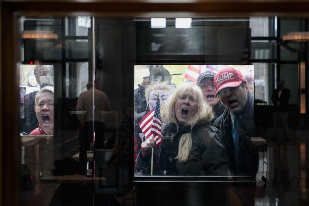 FILE - In this April 13, 2020, file photo Ohio state senate candidate Melissa Ackison, left, and other protesters stand outside the Statehouse Atrium where reporters listen during the State of Ohio&#039;s Coronavirus response update at the Ohio Statehouse in Columbus, Ohio. The unprecedented national effort to shut down much of daily life to slow the spread of COVID-19 is prompting a growing number of protests. (Joshua A.