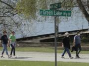 Some people wearing masks, and some not, walk on a pathway at Green Lake Park, Friday, April 10, 2020, in Seattle. In hopes of stopping group gatherings and exercise where social distancing isn&#039;t being practiced, City of Seattle officials plan to close the entire park and more than a dozen others over the Easter weekend to try and continue slowing the spread of the coronavirus, but many fear warm weather and weariness of Washington state&#039;s stay-at-home order could still drive people outside. (AP Photo/Ted S.