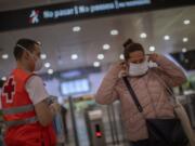 A passenger receives a face mask distributed by a red cross volunteer at the main train station in Barcelona, Spain, Tuesday, April 14, 2020. Face mask distribution in train and bus stations continue as factory and construction workers resume their activities in roughly half of Spanish regions emerging from the Easter holiday period. Spain&#039;s left-wing Cabinet is expected to pass new measures to aide smaller business and the self-employed affected by the freezing of economic activity.