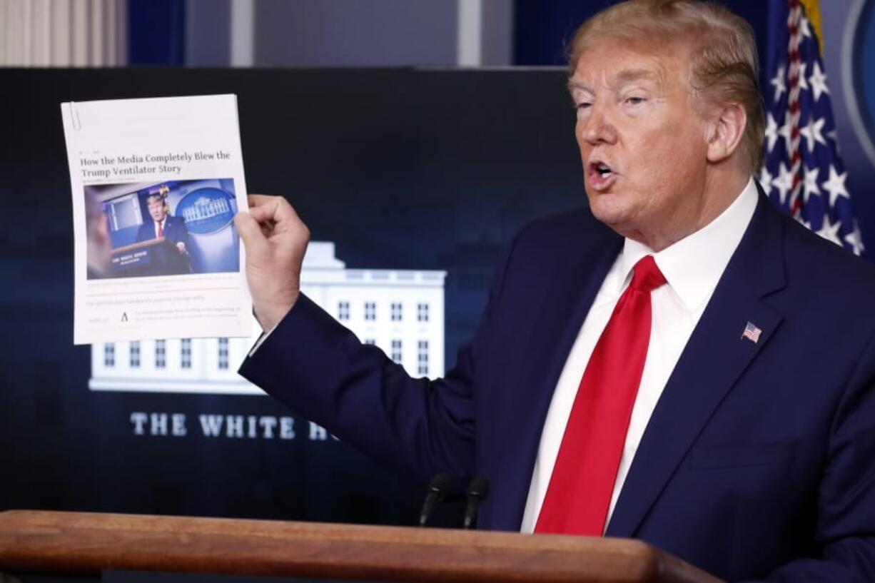 President Donald Trump holds up a news article as speaks about the coronavirus in the James Brady Press Briefing Room of the White House, Monday, April 20, 2020, in Washington.