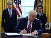 President Donald Trump signs a coronavirus aid package to direct funds to small businesses, hospitals, and testing, in the Oval Office of the White House, Friday, April 24, 2020, in Washington. Sen. Roy Blunt, R-Mo., left, and Jovita Carranza, administrator of the Small Business Administration look on.