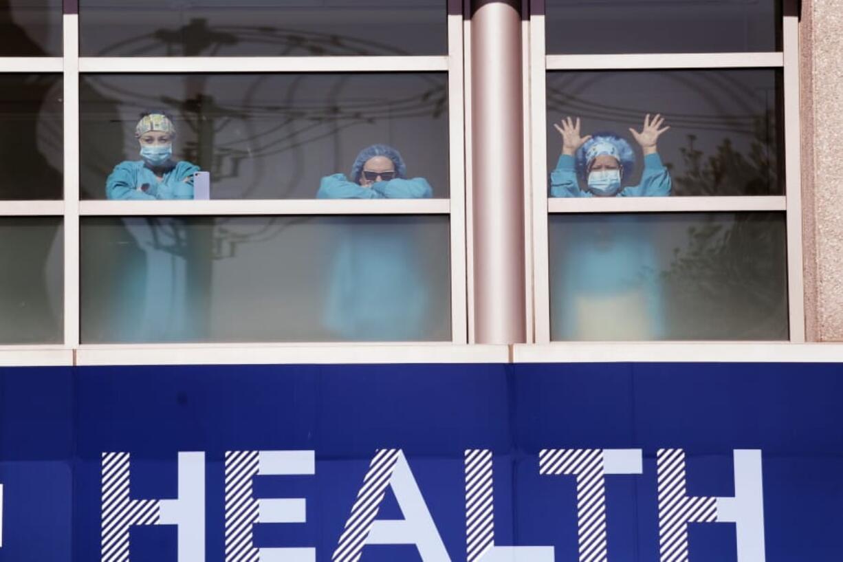 Swedish Medical Center health care workers battling the coronavirus outbreak look on from inside the hospital as first responders gathered outside in support of them Thursday, April 16, 2020, in Seattle. First responders across King County planned to stand outside of 15 hospitals in a show of appreciation for health care workers through the day Thursday.