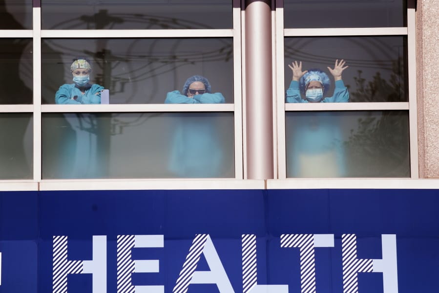 Swedish Medical Center health care workers battling the coronavirus outbreak look on from inside the hospital as first responders gathered outside in support of them Thursday, April 16, 2020, in Seattle. First responders across King County planned to stand outside of 15 hospitals in a show of appreciation for health care workers through the day Thursday.