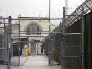 A man does maintenance work between razor wire-topped fences at the Monroe Correctional Complex in Monroe, Wash.