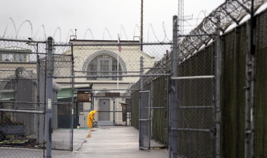 A man does maintenance work between razor wire-topped fences at the Monroe Correctional Complex in Monroe, Wash.