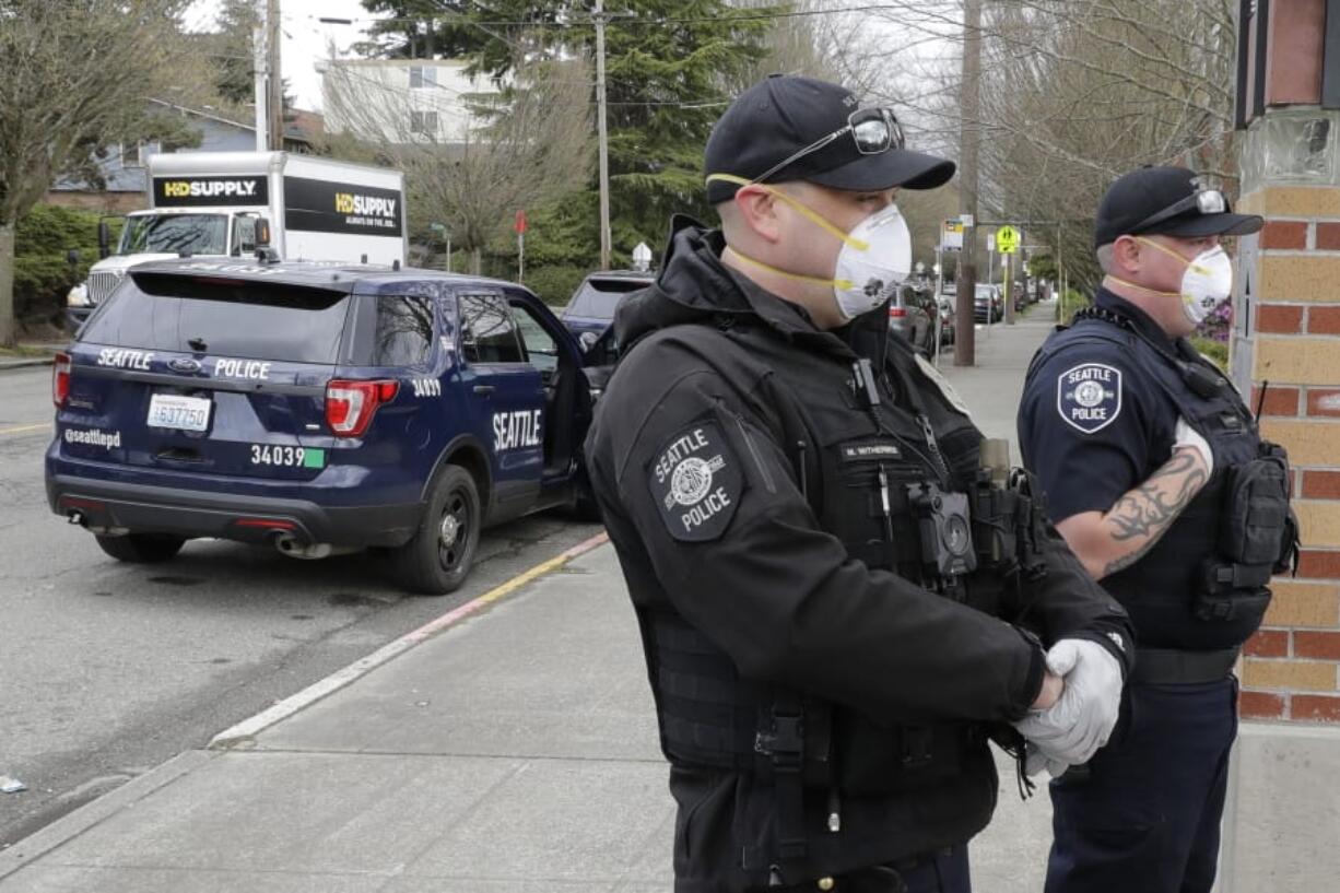 Seattle Police officers wear N95 masks as they listen to conversation during a routine call Thursday, April 2, 2020, in Seattle. As police and fire departments across the country face personnel shortages due to the spread of the new coronavirus, masks and other protective gear are being used to keep officers and firefighters still on the streets safe and healthy. (AP Photo/Ted S.