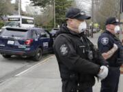 Seattle Police officers wear N95 masks as they listen to conversation during a routine call Thursday, April 2, 2020, in Seattle. As police and fire departments across the country face personnel shortages due to the spread of the new coronavirus, masks and other protective gear are being used to keep officers and firefighters still on the streets safe and healthy. (AP Photo/Ted S.