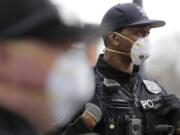 Seattle Police officer Rosell Ellis, right, wears an N95 mask as he listens to conversation during a routine call Thursday, April 2, 2020, in Seattle. As police and fire departments across the country face personnel shortages due to the spread of the new coronavirus, masks and other protective gear are being used to keep officers and firefighters still on the streets safe and healthy. (AP Photo/Ted S.