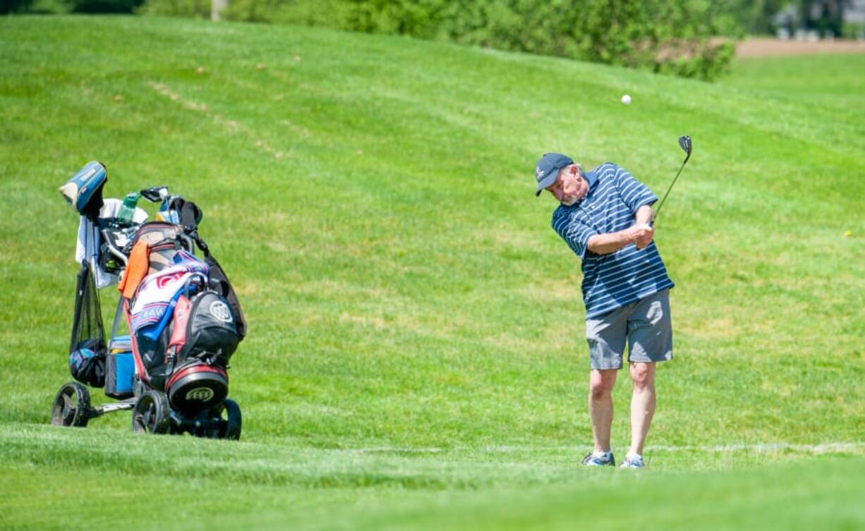 Washougal resident Mark Fennell pitches into the 10th green at Tri-Mountain Golf Course on Tuesday in Ridgefield. Fennell has been staying active by golfing in Oregon but enjoyed the sunshine as golf courses reopened Tuesday around Washington.