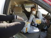 Mary Silva, left, with Pathways LA hands out diapers and hand sanitizers to Irma Juarez, who has two children ages 3 and 4, as Pathways LA and Hello Bello are distributing thousands of diapers to families in need April 14 as the coronavirus diaper shortage highlights tough choices for Los Angeles families.