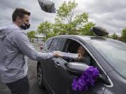 Camas High School girls basketball coach Scott Thompson, left, who owns a local cap-and-gown business that serves many Clark County high schools, gives senior Hannah Alhilali, 17, her cap and gown at Heritage High School on May 13.