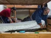 Tyler Taplin, left, and Chad Calhoun make their beds inside the Winter Hospitality Overflow Shelter at St. Paul Lutheran Church in December. Nearly 11,000 safe sleeps occurred at St. Paul or St. Andrew Lutheran Church last winter.