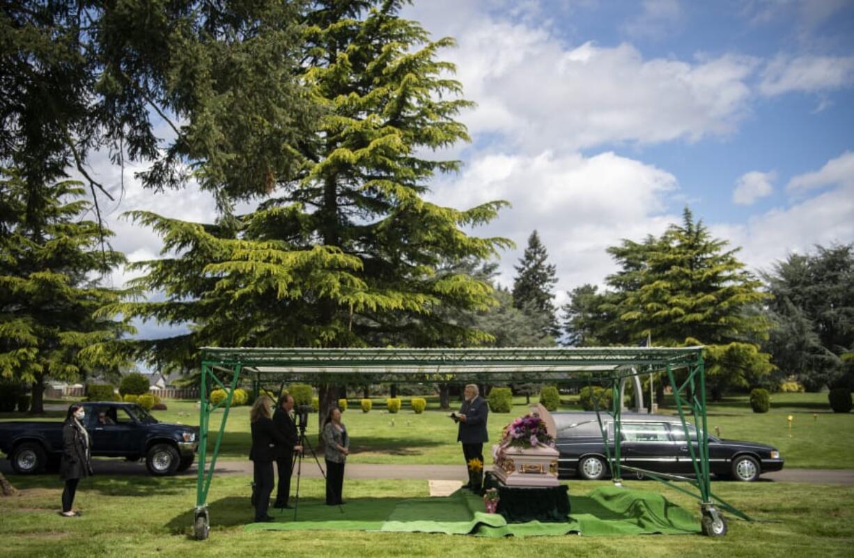 Evergreen Memorial Gardens staff and family members listen as Chaplain Landis Epp leads the burial prayer for Velda Bridger at the cemetery in Vancouver on Monday. Only two family members could stand by the gravesite for the burial, but Evergreen Memorial Gardens also offered a live recording for family to tune in and watch. The recording is also available to the family for three months after the burial.