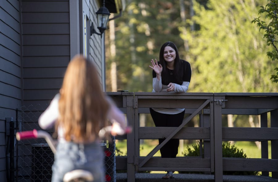 Melanie Zaytsev, 7, rides her bike and visits with her mother, Tiona Gudishvili, at their home in Vancouver. Gudishvili, an ICU nurse, socially distanced herself from her family while she treated a flurry of COVID-19 patients.