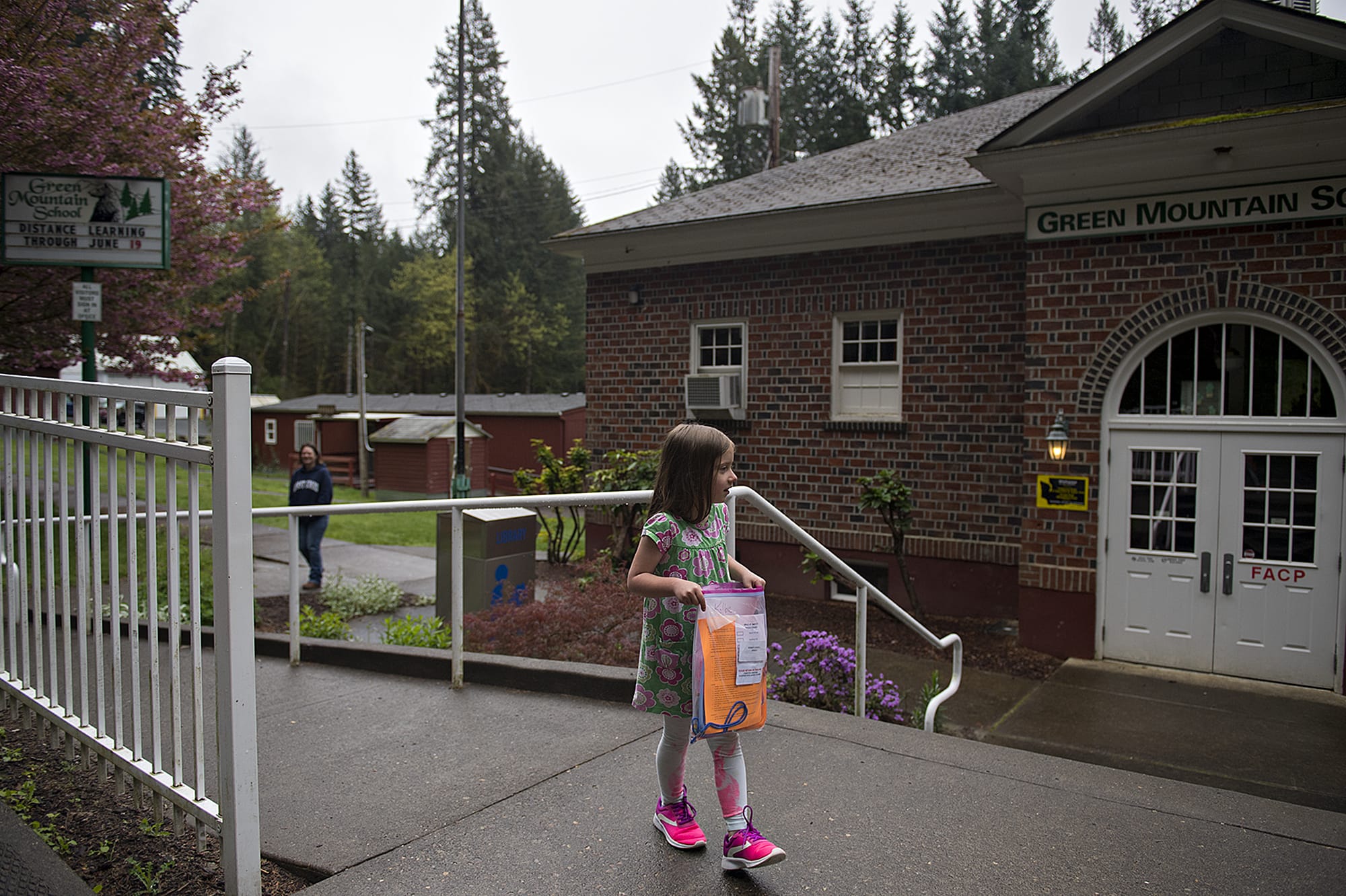 Green Mountain School first-grader Kolbie Bennett, 7, takes the school packet with her assignments to go while visiting the closed campus with her mom, Aeranee, in Woodland on Friday morning, April 24, 2020.
