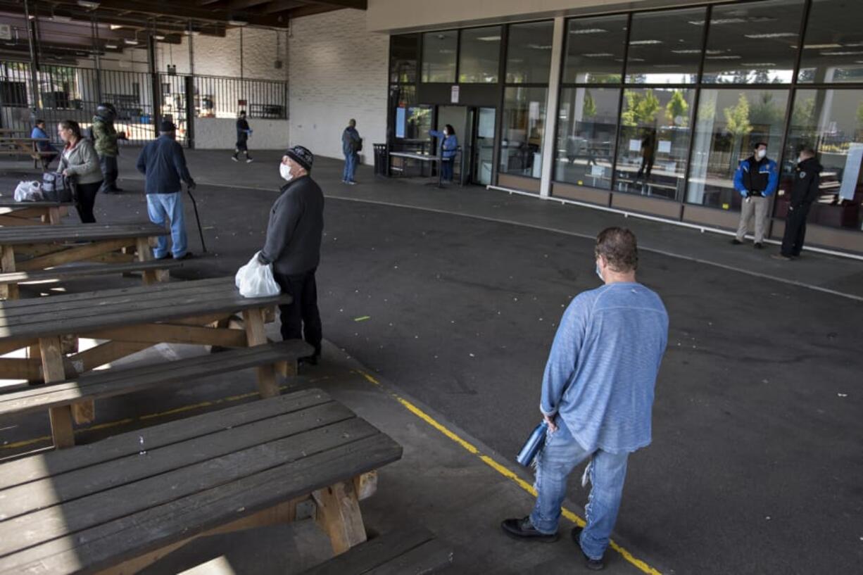 Clients at the Vancouver Navigation Center practice social distancing as they wait in line to take part in the limited services available Tuesday. For two hours, participants were able to pick up their mail, get water and use the toilets.