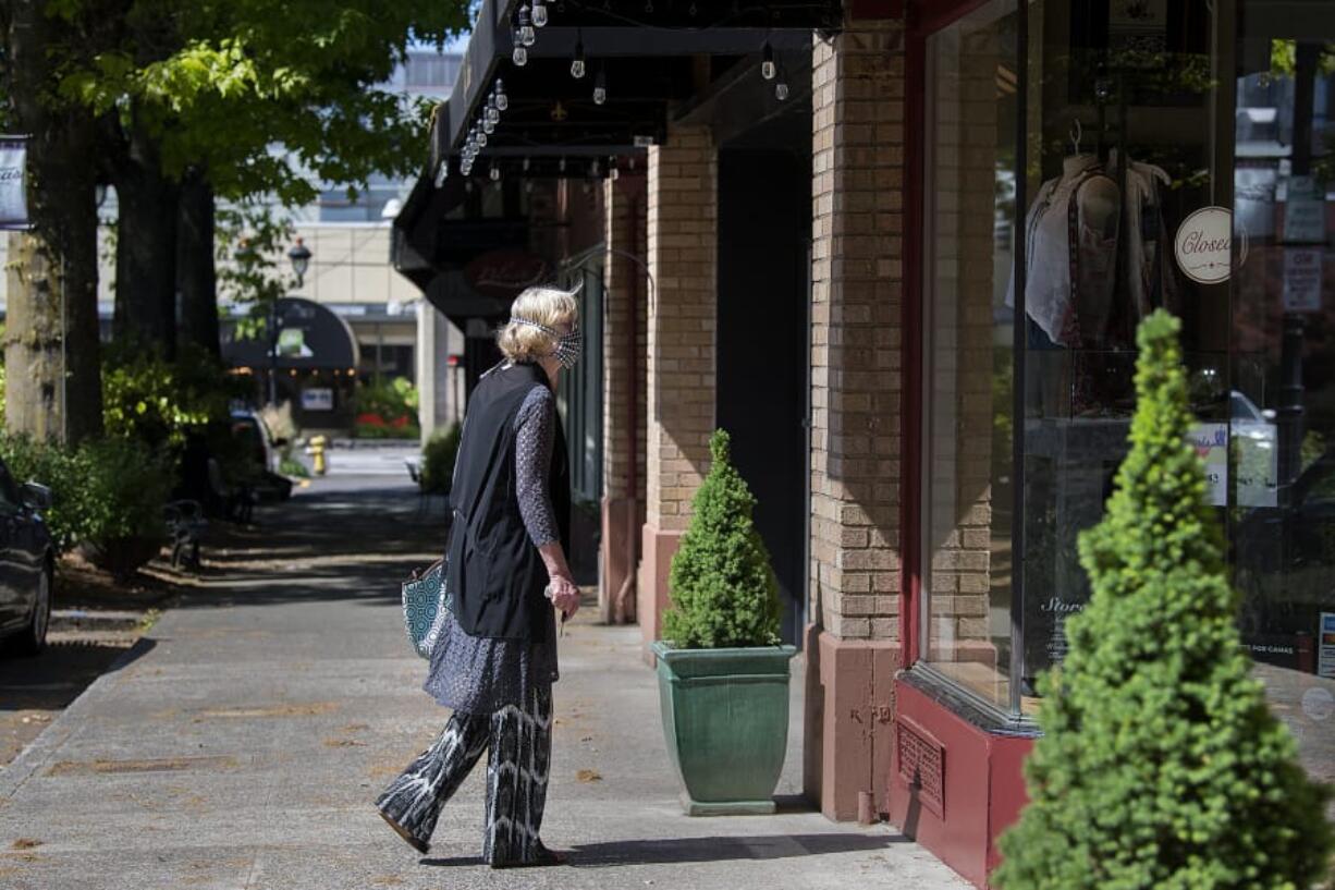 Uta Zuendel, who has lived in Camas since 1974, pauses to check out a window display of a closed boutique as she strolls through a nearly empty Main Street in downtown Camas on May 7.