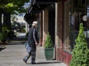 Uta Zuendel, who has lived in Camas since 1974, pauses to check out a window display of a closed boutique as she strolls through a nearly empty Main Street in downtown Camas on May 7.