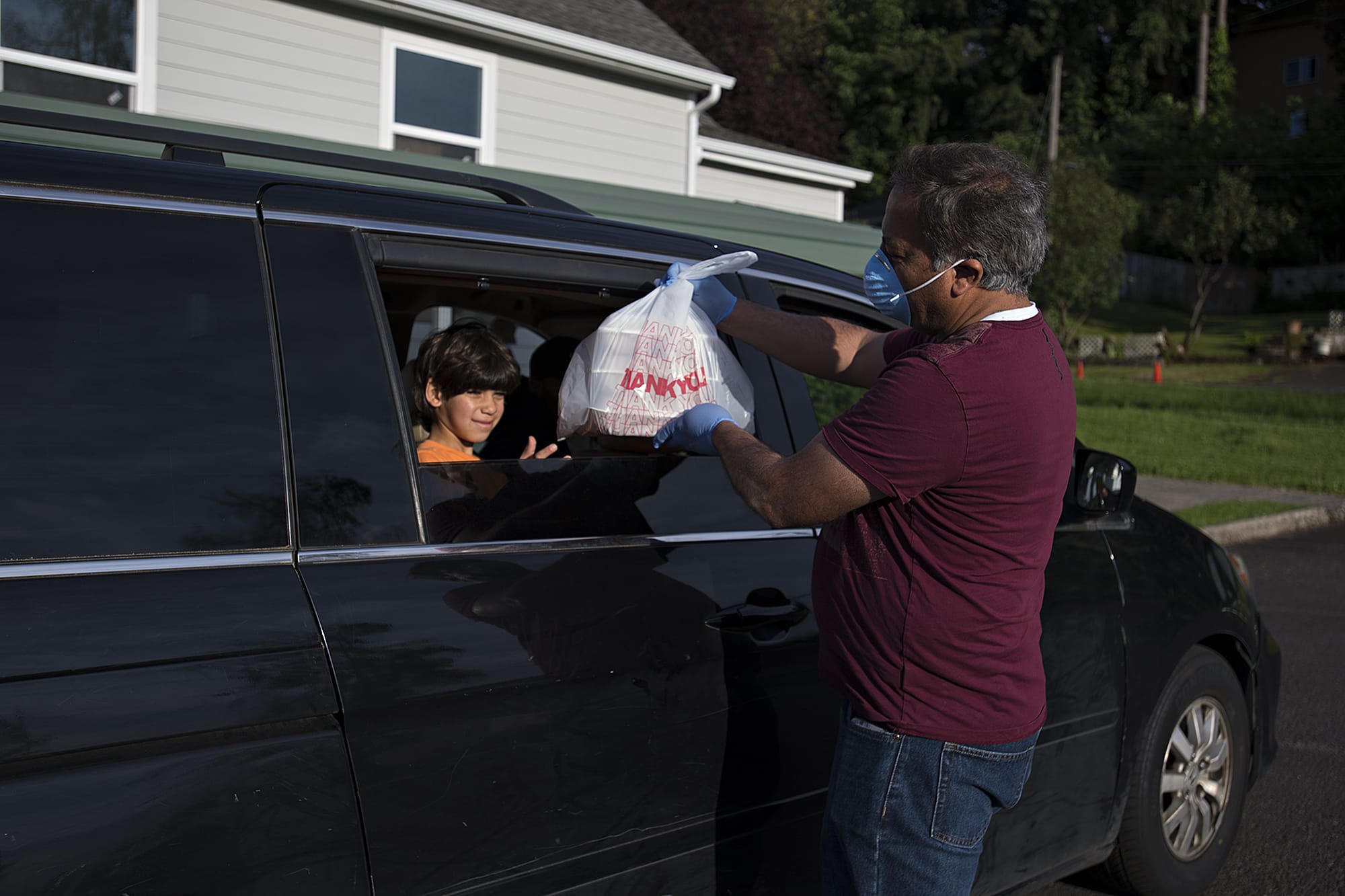 Abdullah Hariri, 7, left, helps collect meals for his family from treasurer Ahmad Qayoumi at the Islamic Society of Southwest Washington on Sunday evening, May 17, 2020. The local mosque is doing meals-to-go for Ramadan this year because of concerns about COVID-19.