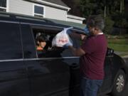 Abdullah Hariri, 7, left, helps collect meals for his family from treasurer Ahmad Qayoumi at the Islamic Society of Southwest Washington on Sunday evening. The local mosque is giving out to-go meals for Ramadan this year because of concerns about COVID-19.