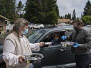 Charlie Raetz, from left, a longtime member of St. Matthew Lutheran Church in Washougal, offers communion to Camas resident Tanya Fritz with the help of Pastor Robert Barber on Sunday morning. St. Matthew Lutheran Church, a small church in Washougal, offered its first drive-in church service that also included music, a message and cookies to-go for those in attendance.