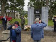 Veteran Marlene Varga of the Community Military Appreciation Committee, facing with phone, broadcasts a scaled-down version of the annual Memorial Day observance over Facebook live as taps is played at Fort Vancouver National Historic Site on Monday morning. Varga was joined by veteran Michael Burton, left, Fort Vancouver superintendent Tracy Fortmann, veteran Larry Smith and Mayor Anne McEnerny-Ogle. CMAC was not able to have its annual Memorial Day service because of COVID-19 concerns, so they hoped to share the experience over video. Varga said the holiday is not a day for a celebration but a day to remember those lost. &quot;We never forget,&quot; she said.