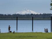 Visitors to Vancouver Lake take in the sunshine and a snow-capped view of Mount Hood while enjoying the day and keeping their distance on Wednesday. The temperature reached 80 degrees Wednesday and will continue to climb today.